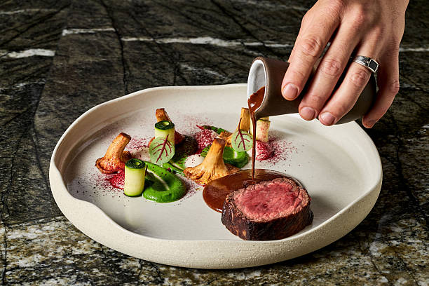 Chef Pouring Sauce on Gourmet Beef Steak with Vegetables Fine Dining