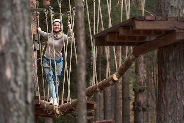 Woman enjoying adventure in a high-ropes course in the forest.