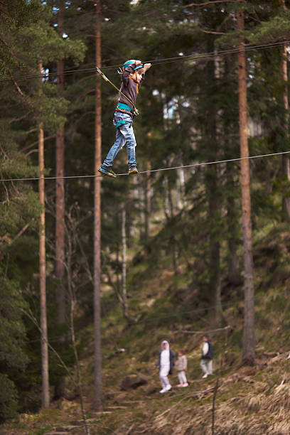 istock Boy balancing on ropes course in forest adventure park. 2244203818