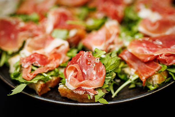 istock Prosciutto and arugula bruschetta on dark plate 2244204303