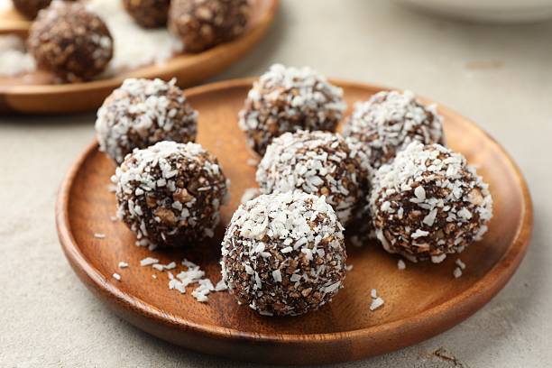 istock Tasty chocolate candies with nuts and coconut flakes on light table, closeup 2244206016