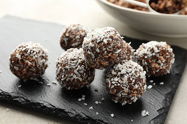 istock Tasty chocolate candies with nuts and coconut flakes on light table, closeup 2244206130
