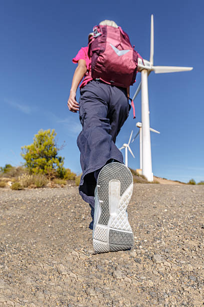 istock Hiker walking on a dirt path towards wind turbines in a scenic landscape 2244206335