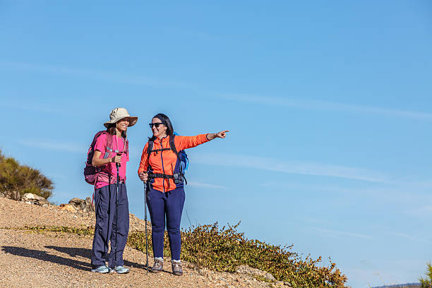 Two female hikers discussing trail navigation in a scenic outdoor setting