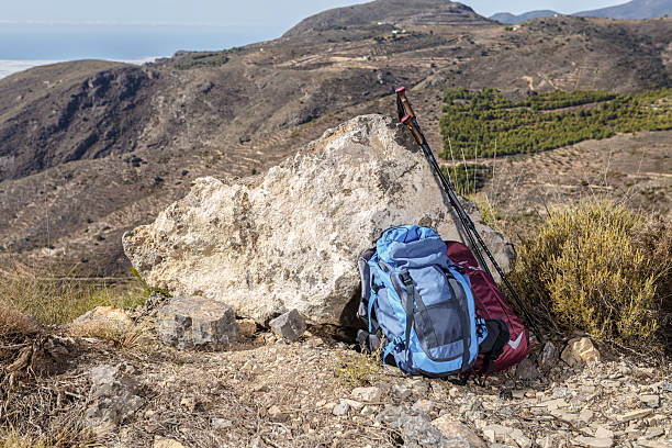 A mountain landscape featuring a backpack and hiking poles against a rocky setting. The scene showcases rugged terrain, inviting outdoor enthusiasts to explore the beauty of nature.