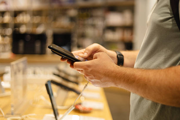 istock Closeup of man testing smartphone at electronics store showcase. 2244207649