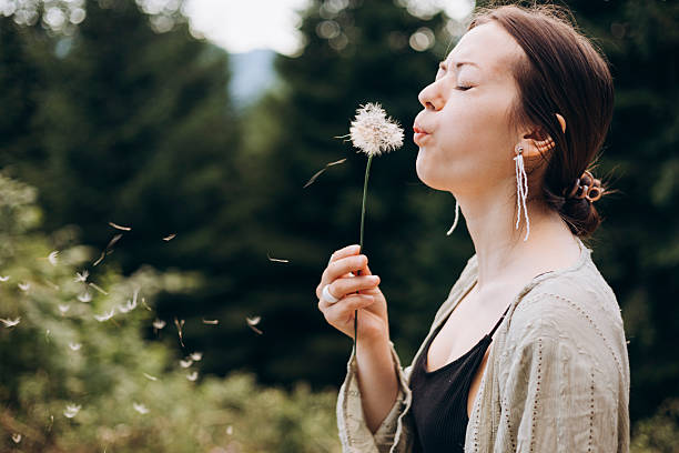 istock Young woman blowing fluffy dandelion seeds in summer forest, copy space. 2244208445