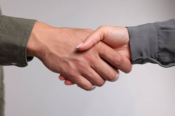 Woman and man shaking hands on light grey background, closeup