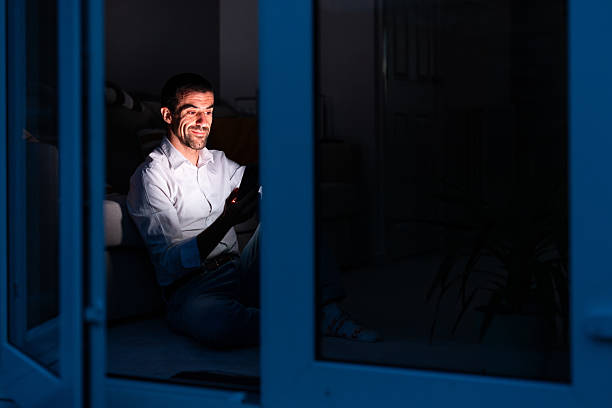 istock Man using smartphone at night sitting on floor by window 2244209318