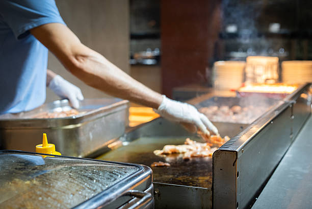 Hand of Chef cooking beef steak on hot pan in front of customers.