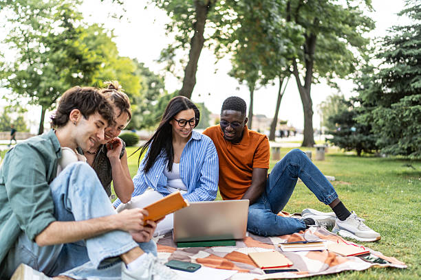 istock Diverse students collaborating outdoors with laptop and books 2244210379