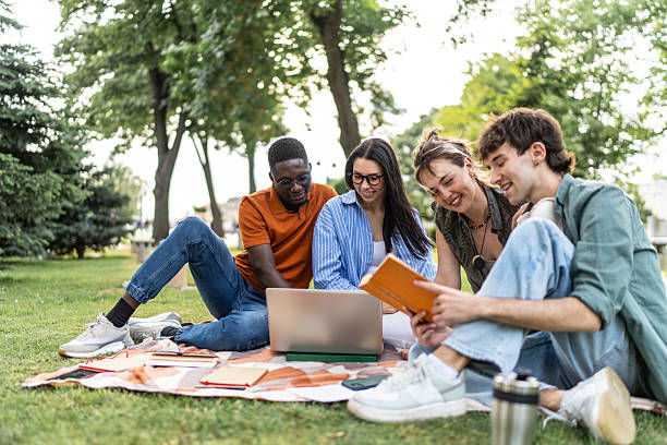 istock Diverse students studying together outdoors on laptop and book 2244210396
