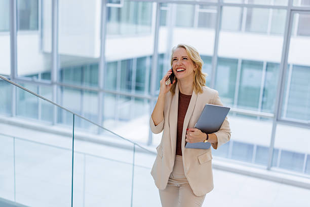 istock Businesswoman talking on phone walking in modern office 2244210457