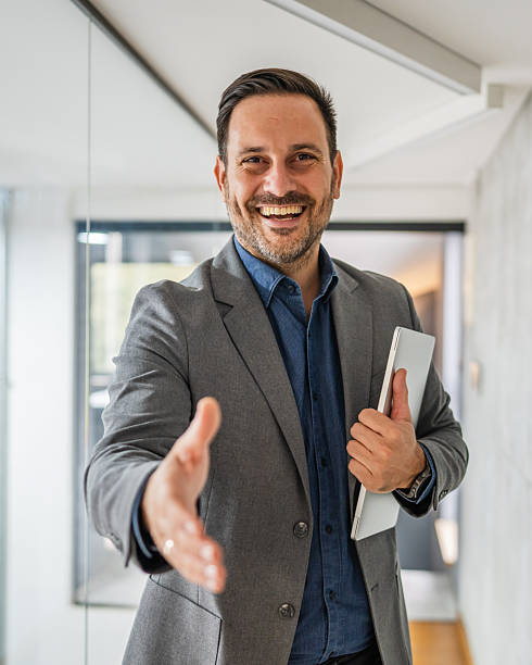 istock Businessman offering handshake, welcoming, smiling in office 2244212350