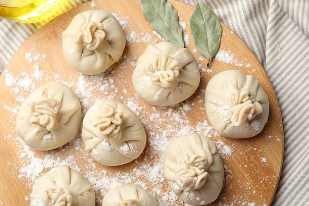 istock Uncooked khinkalis (dumplings) with flour and bay leaves on table, top view 2244213250