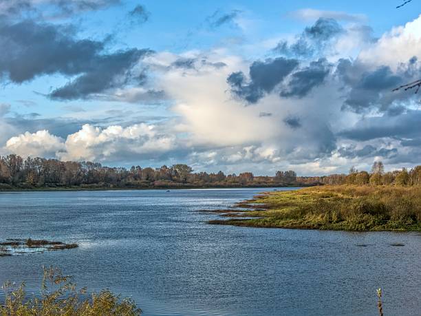 Wide autumn river landscape under a dramatic sky with reflections