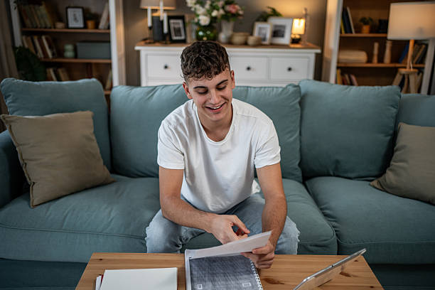 istock Teenager smiling while doing homework in living room 2244215313