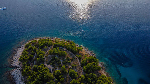 Rugged rocky shore and the sea transitions from a deep, sun-drenched blue to a clear, inviting turquoise