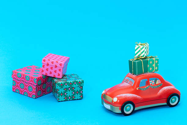 Christmas presents loaded onto the roof of a red car with other Christmas gift boxes