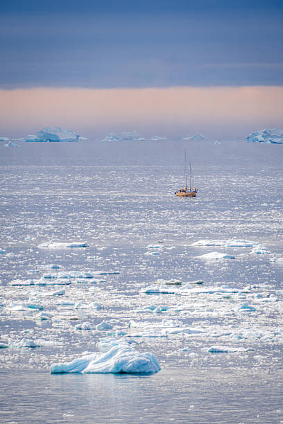 istock Vertical picture of a yellow sailboat gliding past distant glaciers under split sky 2244227370