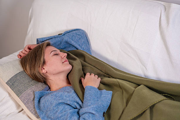 istock Relaxed Woman Lying on Sofa with Blanket 2244228901