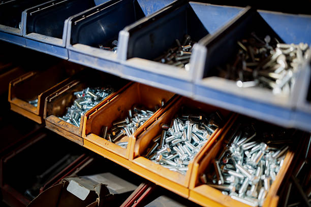Metal bolts and screws sorted in colorful bins on workshop shelf representing construction materials, mechanical parts and organized maintenance equipment storage