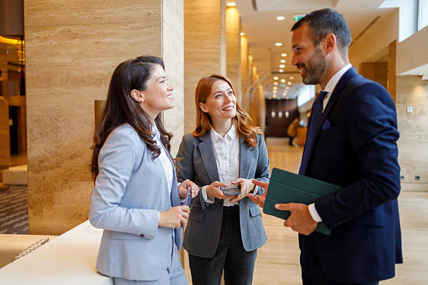 istock Business colleagues collaborating and discussing work in a modern corporate office lobby, smiling during a casual meeting 2244229912