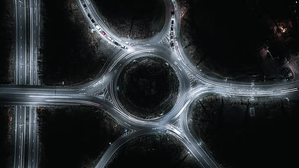 istock Nighttime aerial view of a roundabout with glowing car light trails creating a dynamic cityscape. 2244229962