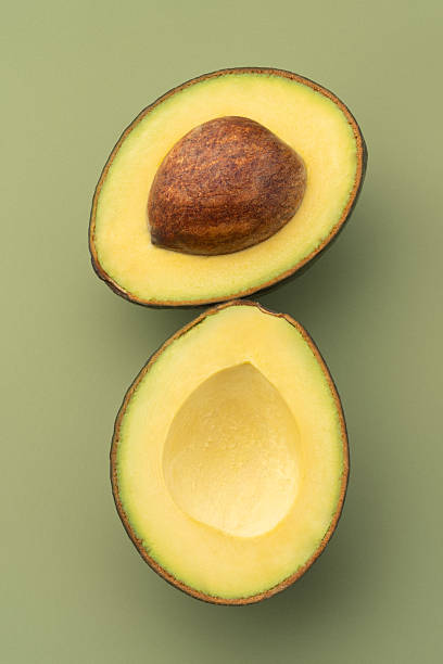istock ripe cut avocado on a green background 2244230039