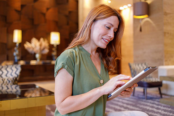istock Woman smiling, browsing digital tablet in a modern hotel lobby, connecting with technology and enjoying leisure 2244230803