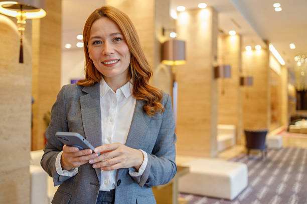 istock Businesswoman looking at camera, holding cell phone, representing communication, technology, and success in a professional setting 2244231521