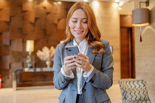 istock Businesswoman checking smartphone in hotel lobby, connecting with clients, managing schedule 2244231663