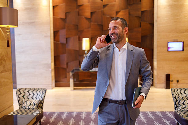 istock Smiling executive using a tablet and talking on a cellphone in a bustling hotel lobby 2244231923