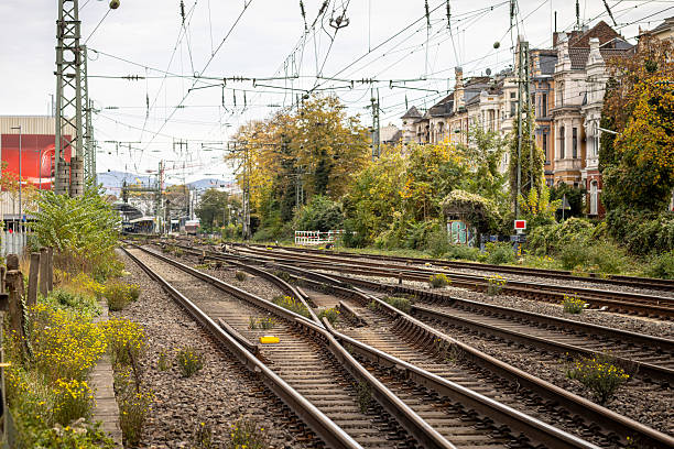 istock Train tracks lined with greenery and historic buildings in an urban setting 2244233937