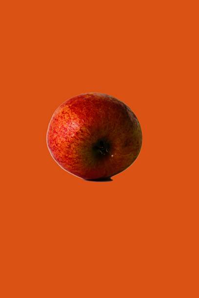 istock Isolated apple on an orange background. Vertical photo with space for text. 2244236519