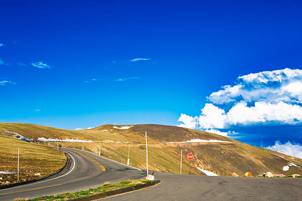 A winding alpine road ascends gently toward the sky, cresting under a radiant cobalt dome. The stop sign stands solitary at the junction, a quiet sentinel at 12,000 feet — marking both an end and a beginning. The land is sparse, the light unbroken, and the sky seems infinite. This image captures a moment of meditative pause: the summit reached, yet the horizon still calling. It’s the distilled essence of arrival — serenity, simplicity, and space to breathe.