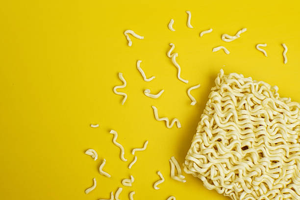 istock Raw instant noodles with crumbs on yellow background, flat lay composition 2244246894