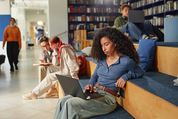 istock Young Adult Woman Studying on Laptop in Modern Library Setting 2244252857