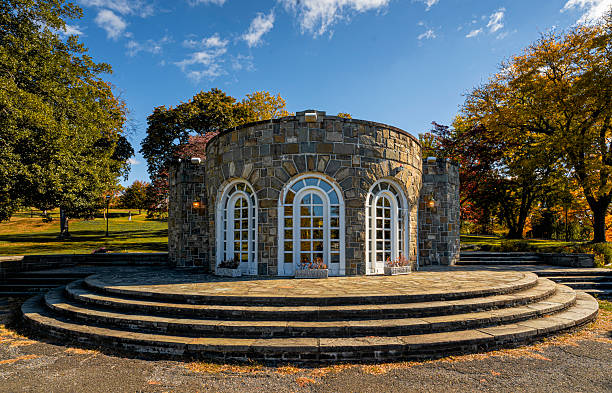 Newburgh, NY - US - Oct 25, 2025 The Polly's Shelter House at Downing Park, a charming natural stone pavilion with arched windows and curved steps, surrounded by autumn trees in warm light.