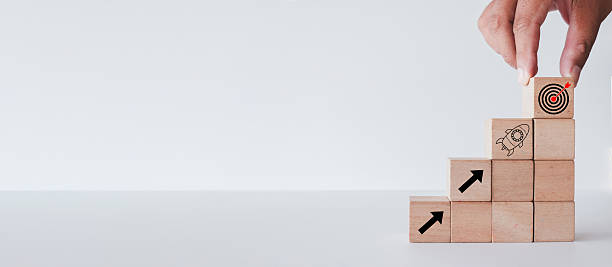 istock Business Growth and Success: Hand Stacking Blocks with Arrow, Rocket, and Target Icons 2244253675