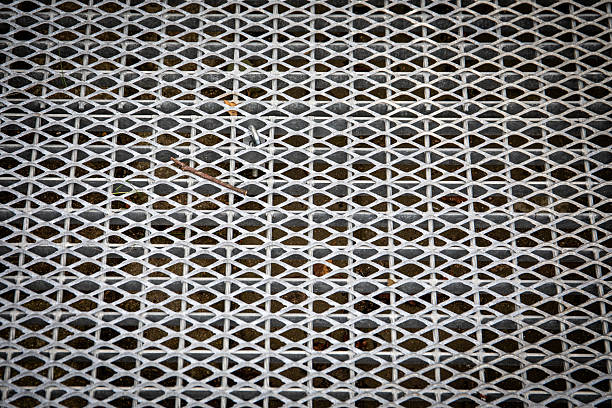 Galvanized metal grating surface for pedestrian walkway ramp or crossing providing drainage durability and safety with industrial texture pattern.
