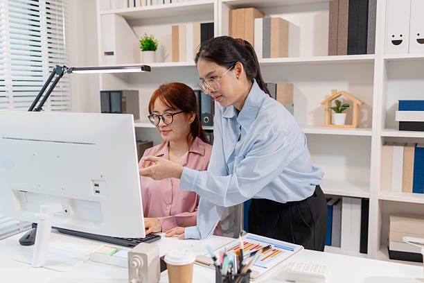 istock Two Asian office colleagues working together in the same department, reviewing documents and discussing project details during a team meeting, showing professional collaboration and teamwork. 2244254305