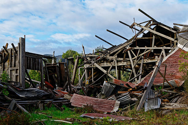 Corrugated iron has fallen off the framing of a building and is strewn across the site.