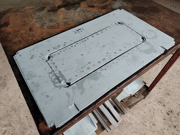Precision cut sheet metal part on a rusty industrial workbench for manufacturing.