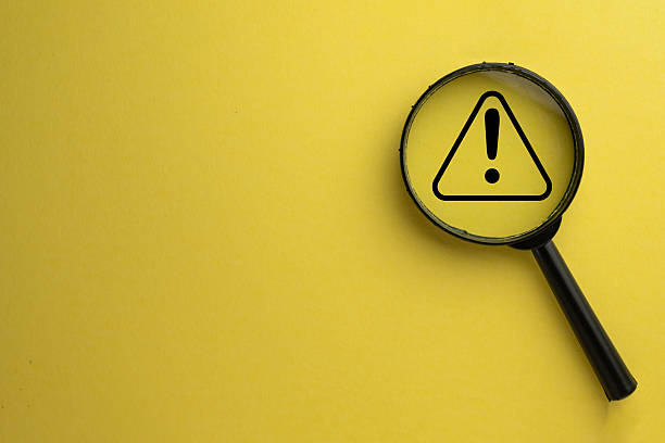 istock Focus on Risk: Magnifying Glass over Warning Alert Icon on Yellow Background.,copyspace for put text or logo.,use for web,banner. 2244254867