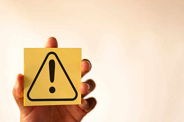 istock Risk and Safety Concept: Hand Holding Sticky Note with Warning Alert Icon.,copyspace use for web,banner,poster. 2244255196