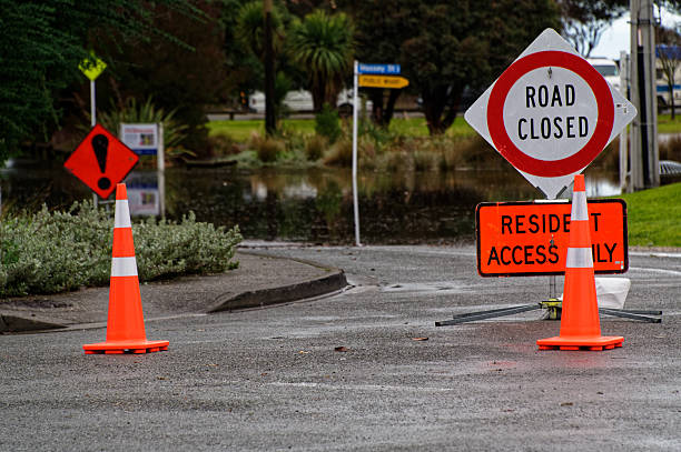 istock Two orange traffic cones help block off a flooded street. 2244256873