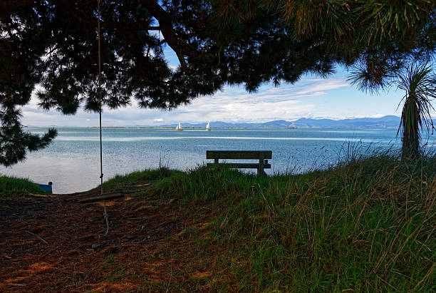 Summer fun, yachts sail out in the bay, an empty chair waits for someone to sit.