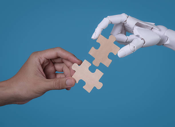 istock Human and Robot Hands Connecting Two Puzzle Pieces: AI and Human Collaboration 2244261115