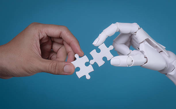 istock Human and Robot Hands Connecting Two Puzzle Pieces: AI and Human Collaboration 2244261124
